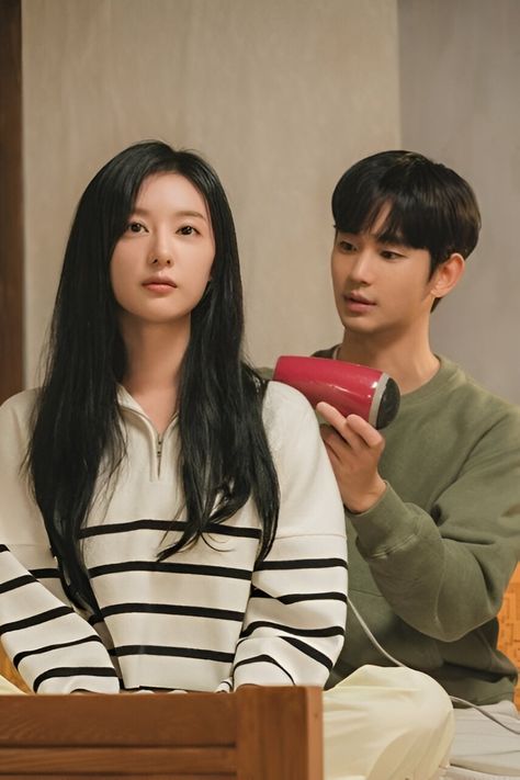 This contain Kim Soo Hyun and Actress Kim Ji Won sitting on a bed one holding a hair dryer and the other looking at something