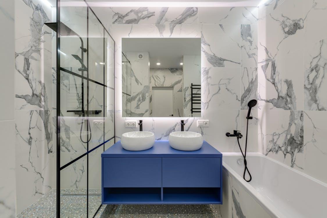 Free Modern bathroom interior featuring marble walls, dual sinks, and a glass shower. Stock Photo