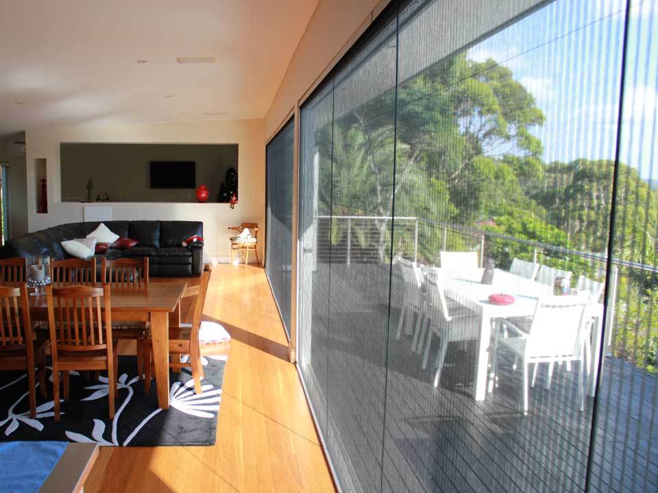 Retractable screen doors installed on large sliding doors, showing indoor dining area and outdoor balcony views
