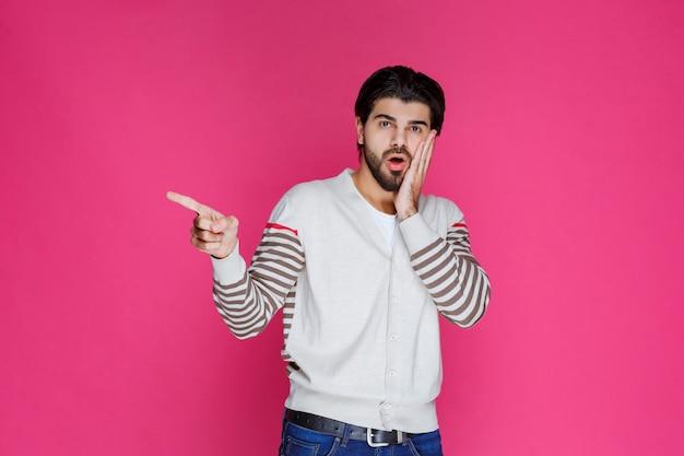 Man in white shirt pointing and presenting someting on the left side. 