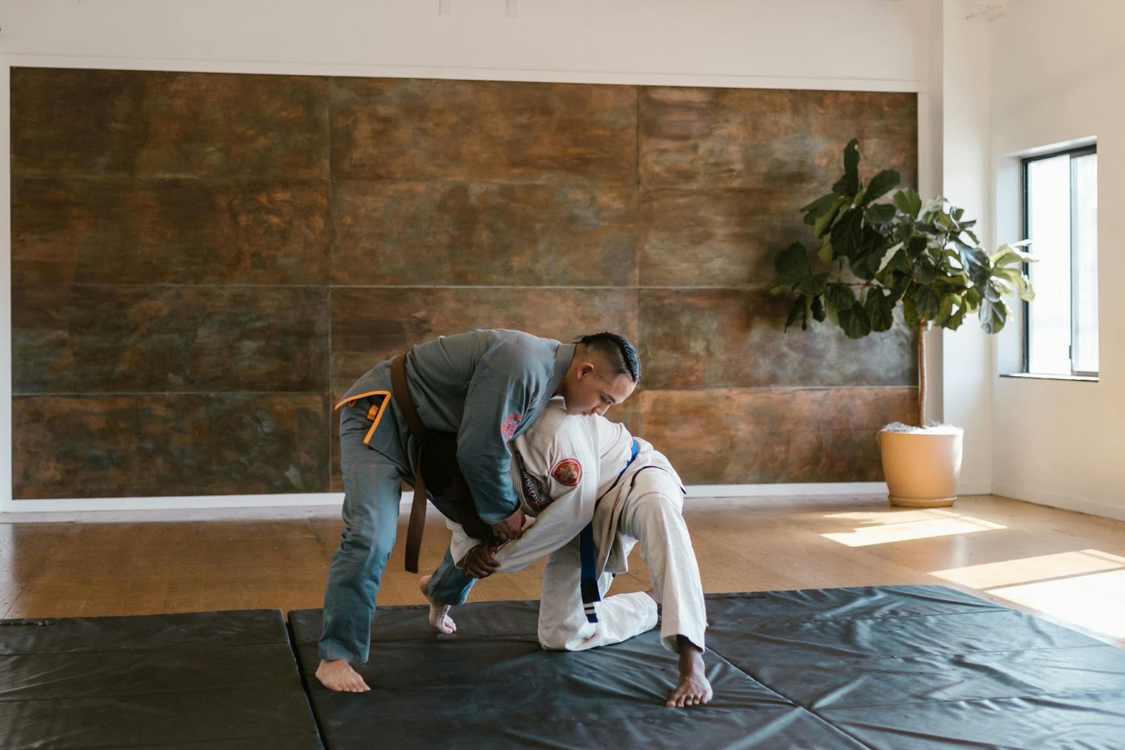 Two martial arts practitioners grapple in a focused training session.