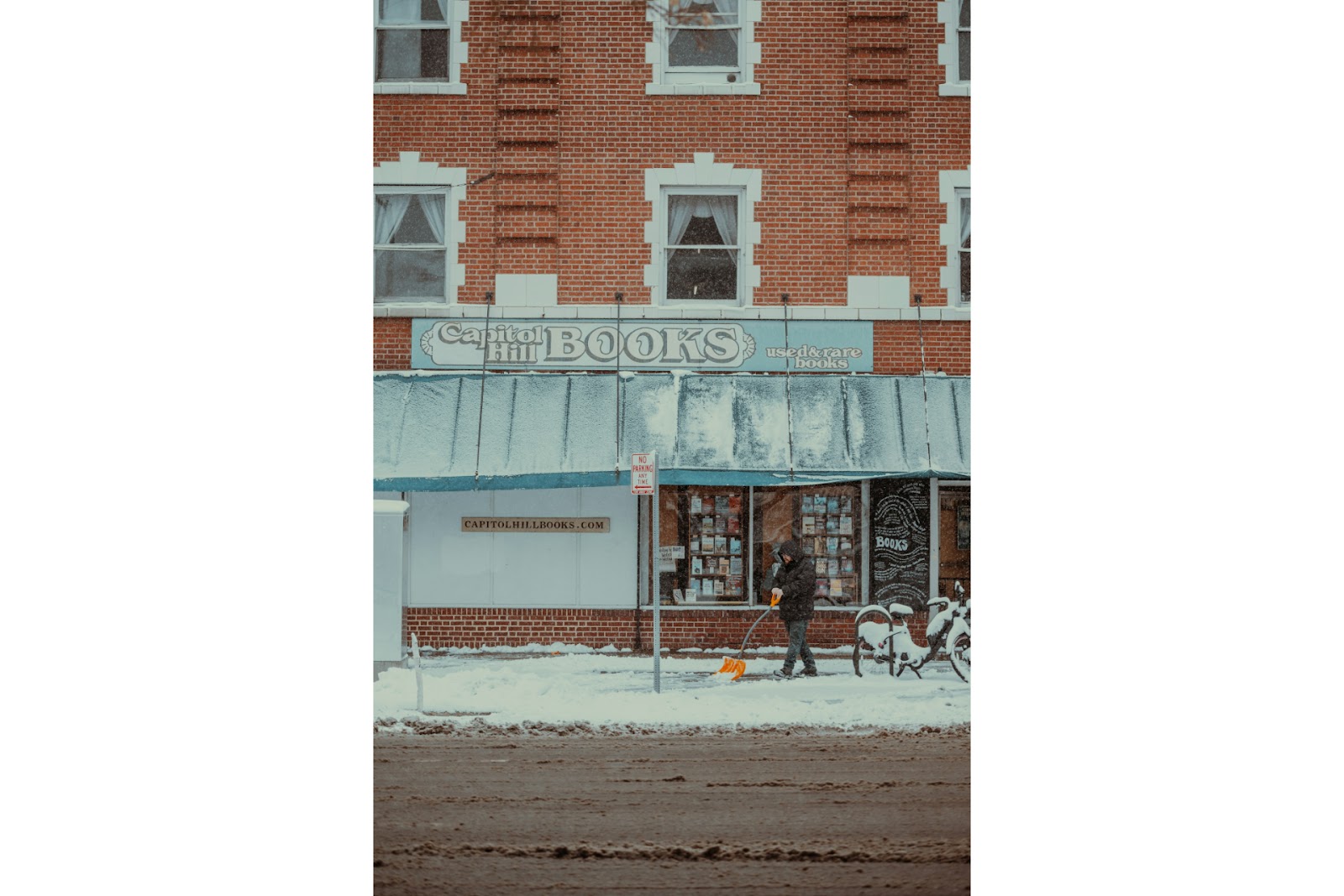 A person using one of the best snow shovel in front of a book store.