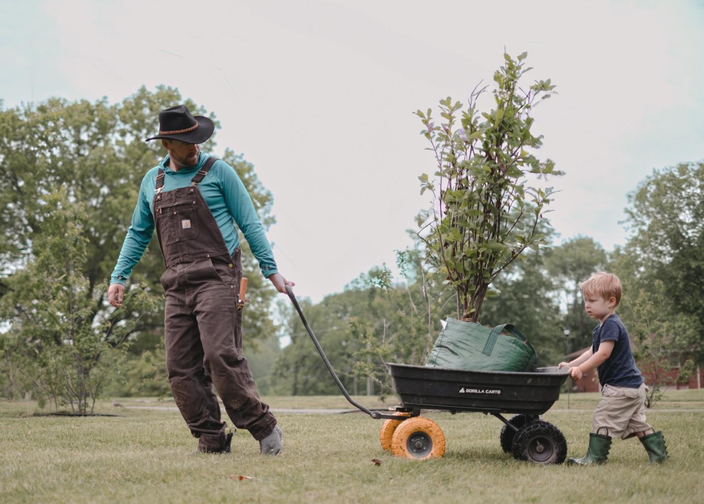 A person pushing a small child in a wheelbarrow AI-generated content may be incorrect.
