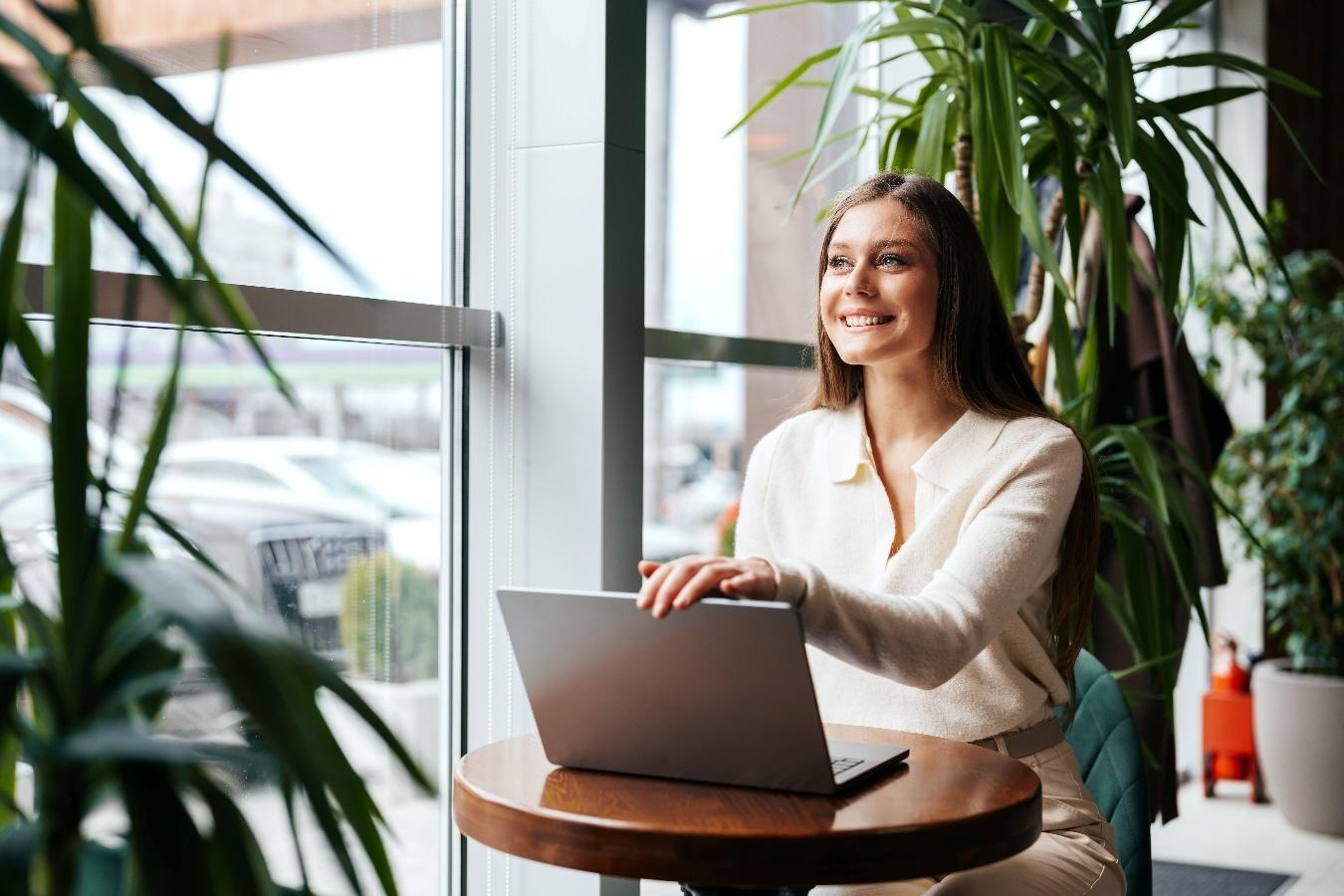 Mujer trabajando en un espacio moderno con plantas, ideal para nómadas digitales que rentan departamentos en CDMX