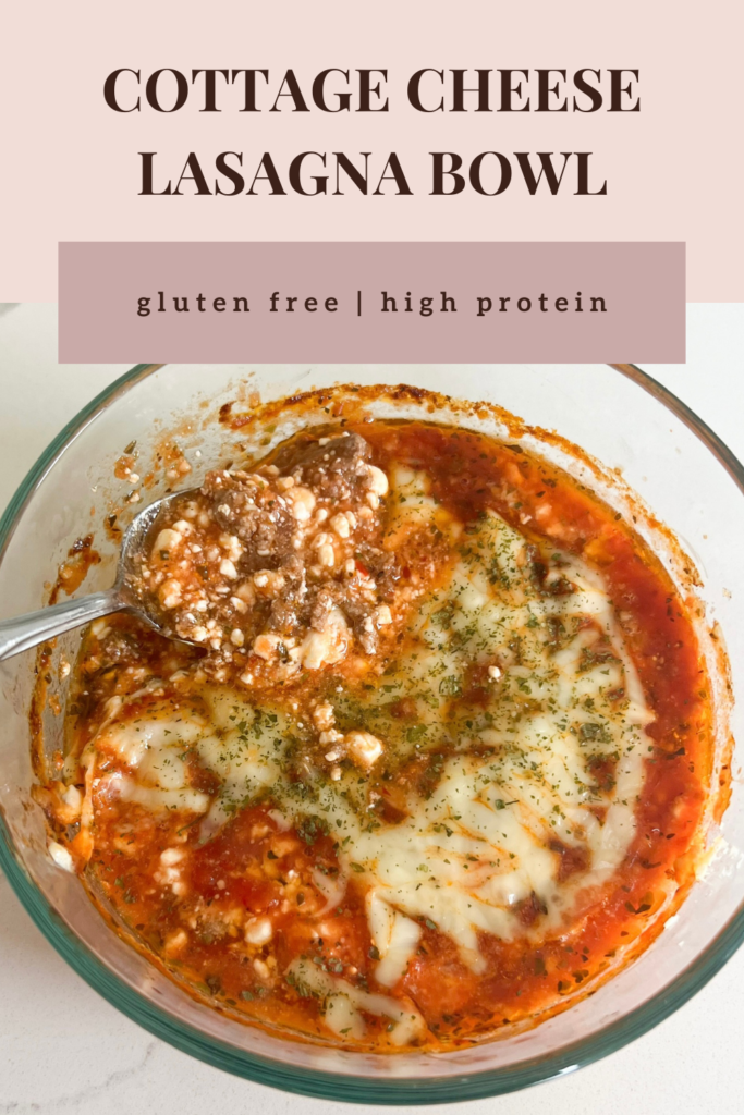 This healthy cottage cheese lasagna bowl is gluten free, high protein, low carb, keto, and single-serve. In a large glass bowl is the lasagna after baking - red marinara sauce bubbly, cottage cheese texture, herbs, melted cheese, and ground beef poking through. It looks like a classic lasagna but in the bowl. 