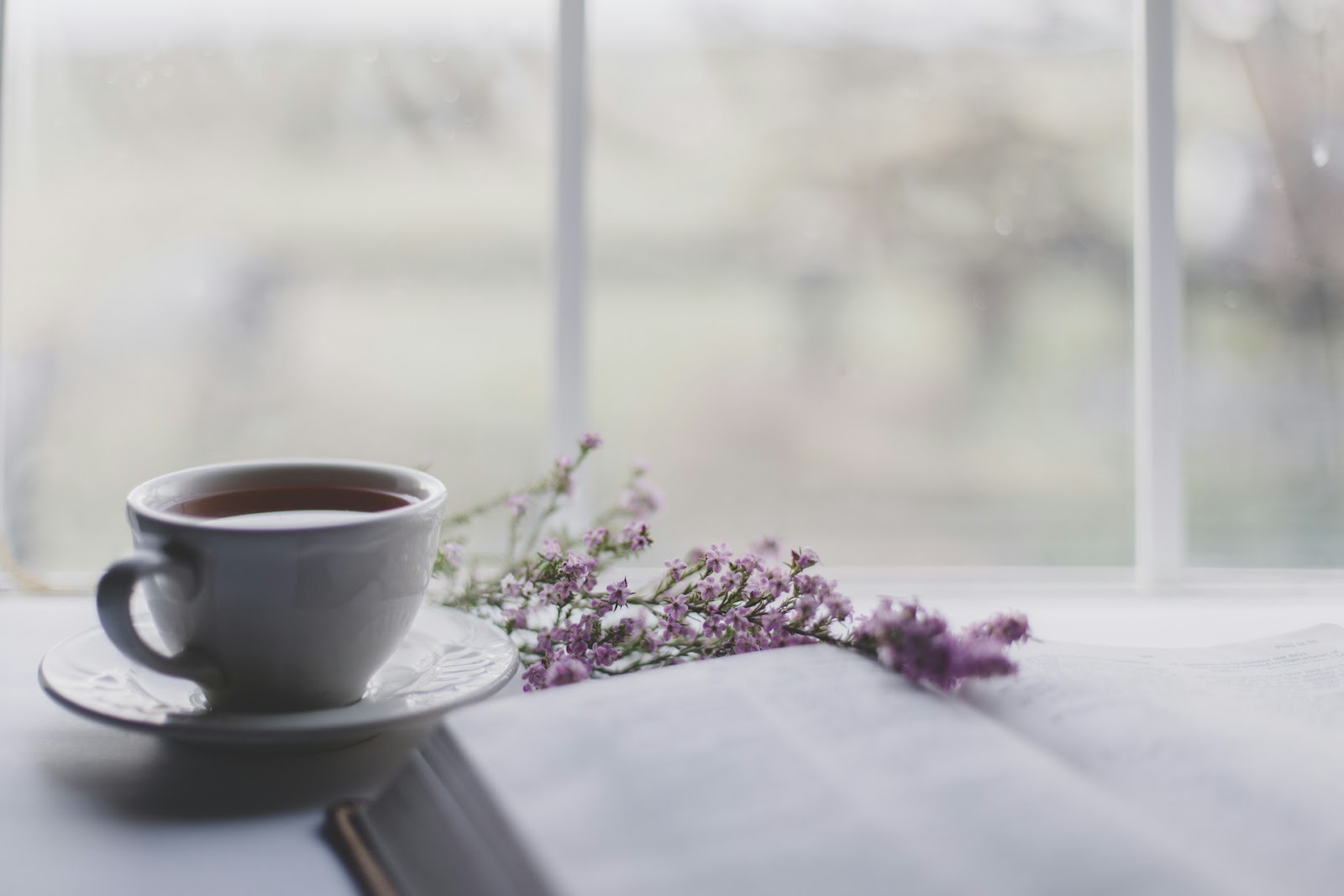 A cup of tea by a window with sprigs of lavender next to it