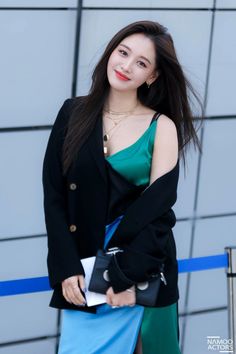 This  contain an image of  Kim Jaekyung standing in front of a wall wearing a black jacket and blue skirt with her hand on her hip