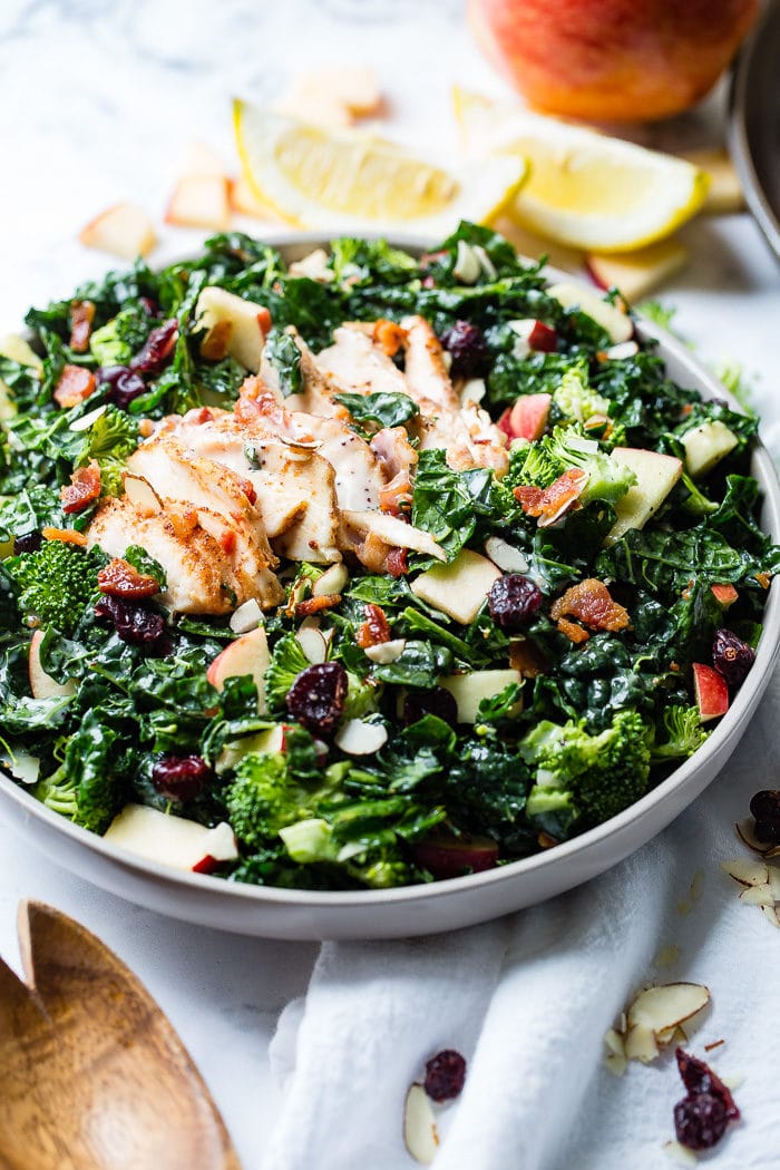 A photo of a kale salad loaded with apples, bacon, cranberries and smoked chicken.