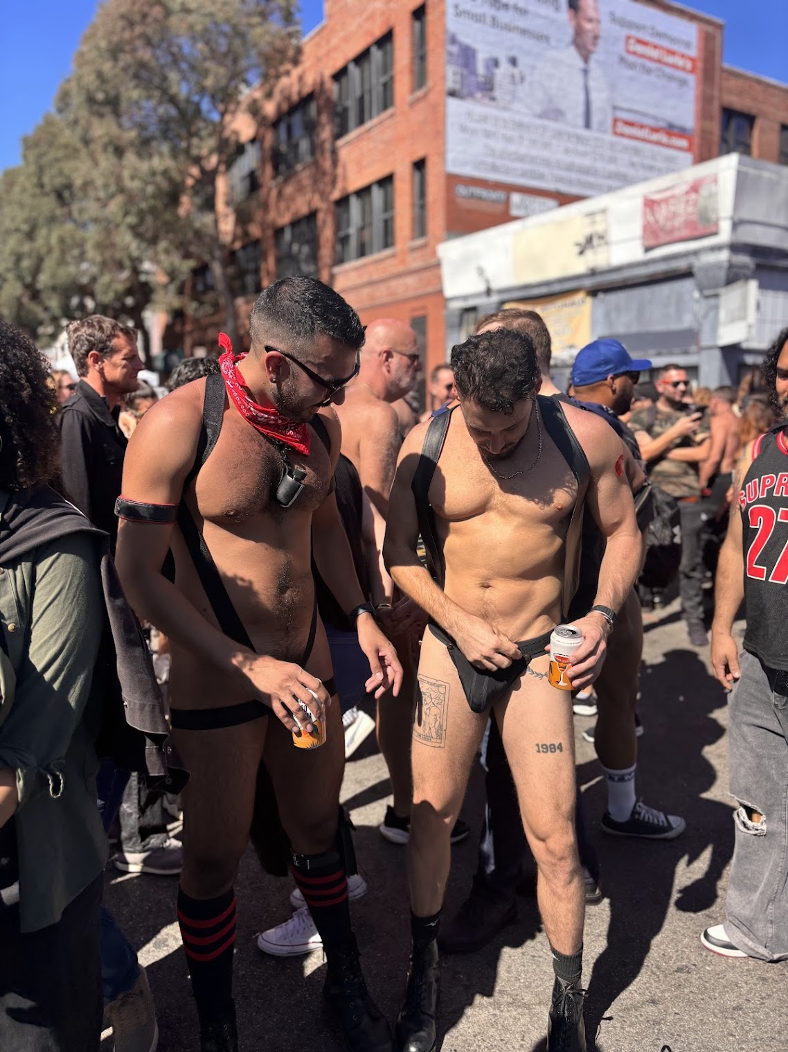 gay xxx onlyfans content creator Phil in tiny bdsm leather harness and fisting hankerchief comparing jockstrap with anonymous gay muscle stud in black jockstrap out on the street in folsom street fair 2024