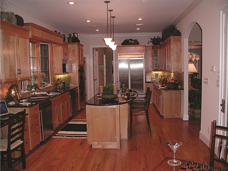 The kitchen offers stainless steel appliances, wooden cabinetry, and a center island topped with small glass pendants.