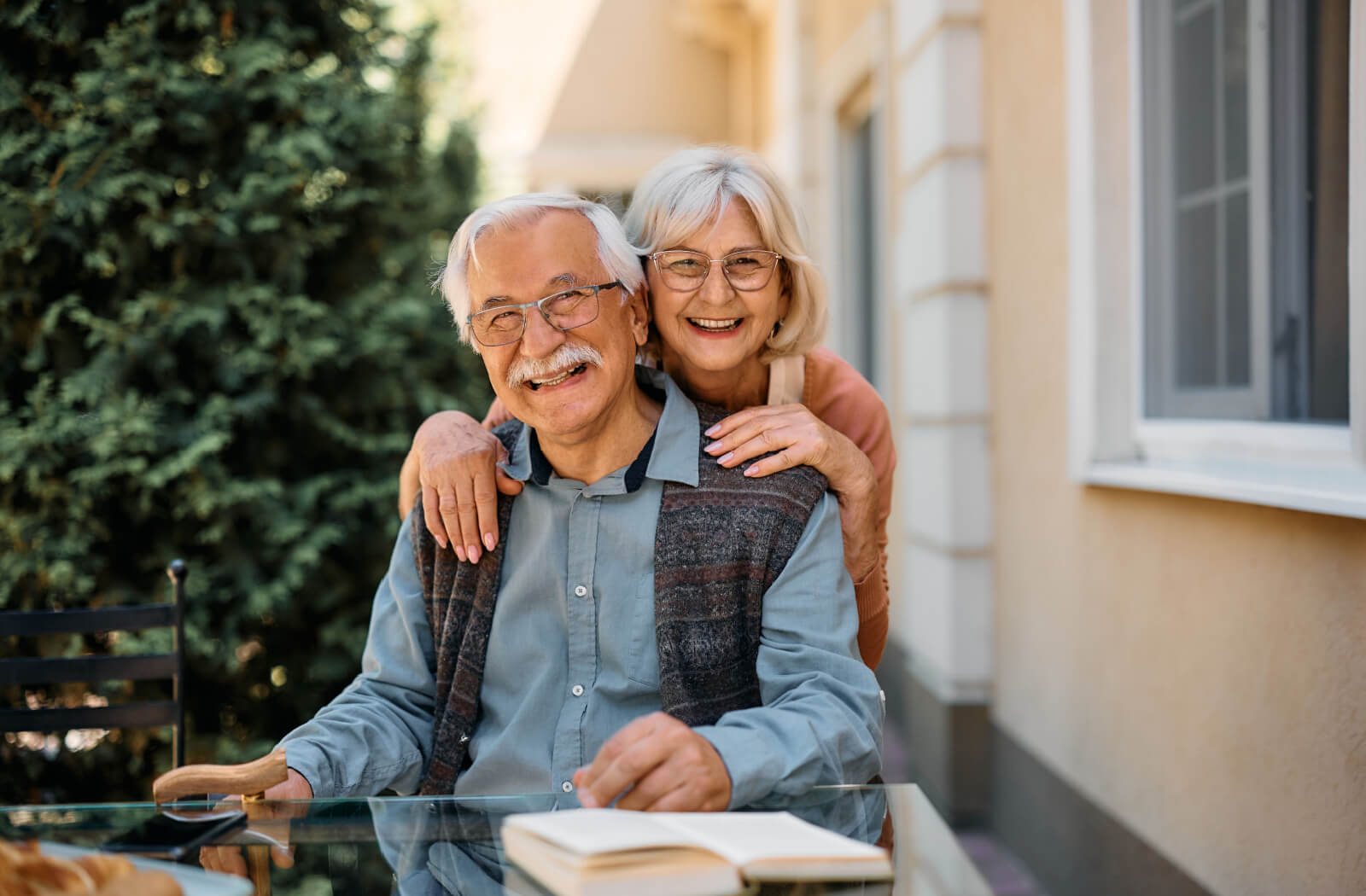 An older couple smiling outdoors after a recent move to senior living to prevent caregiver fatigue.