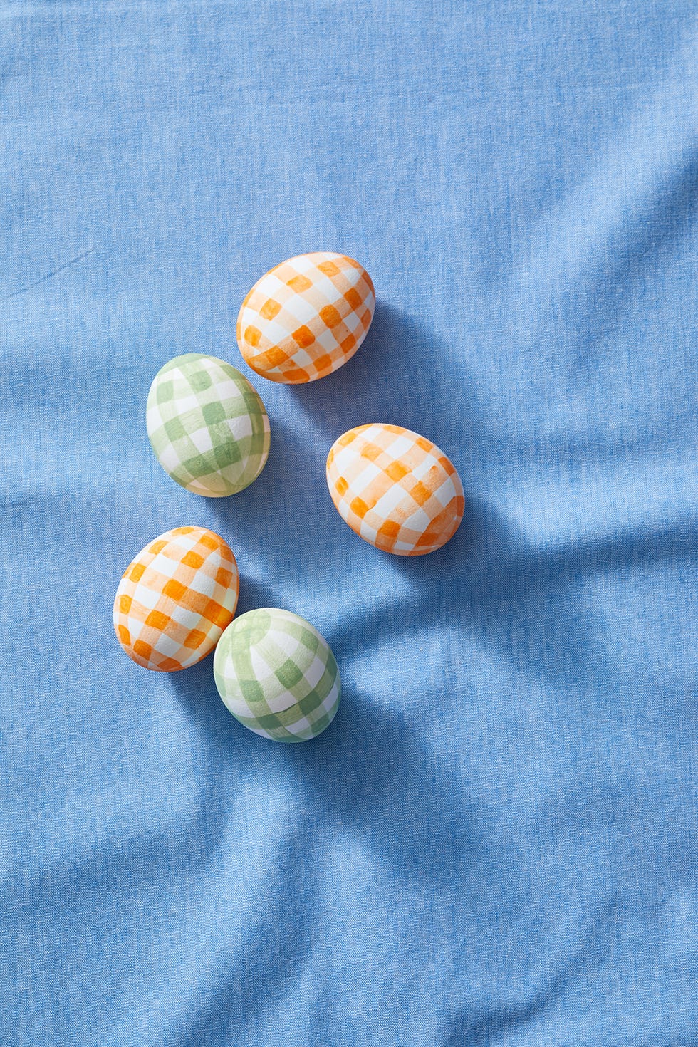 easter egg hunt ideas, five orange and green gingham eggs on a blue cloth