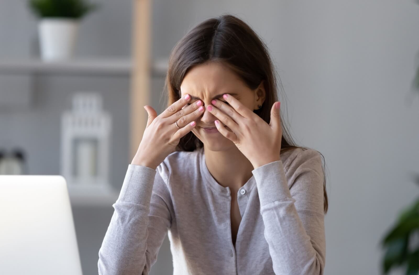 A person with eyelash extensions rubbing their eyes from irritation due to blepharitis