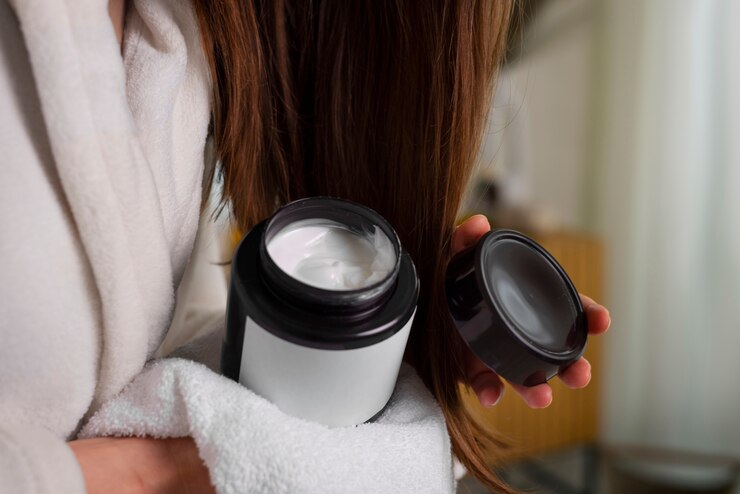 Woman holding hair mask bottle with towel