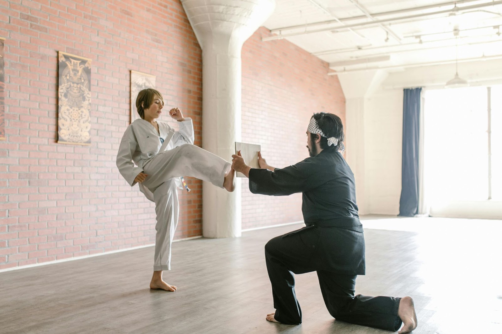 A martial arts instructor training a student how to kick