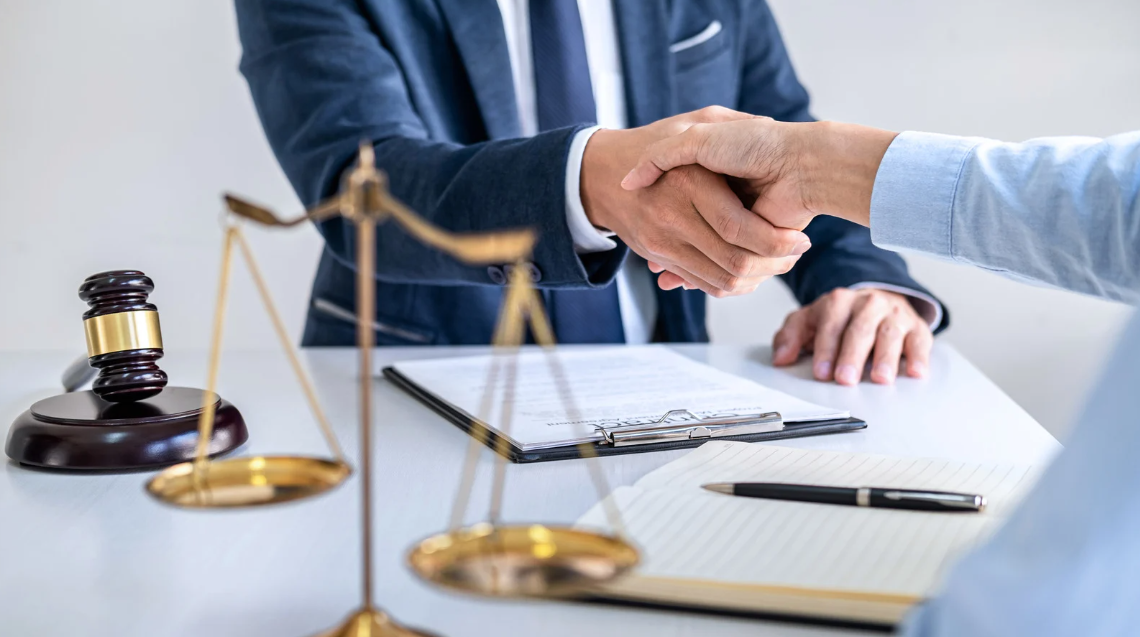 (Attorney and client shaking hands across a desk, symbolizing legal support and trust in a civil rights or police misconduct case.)