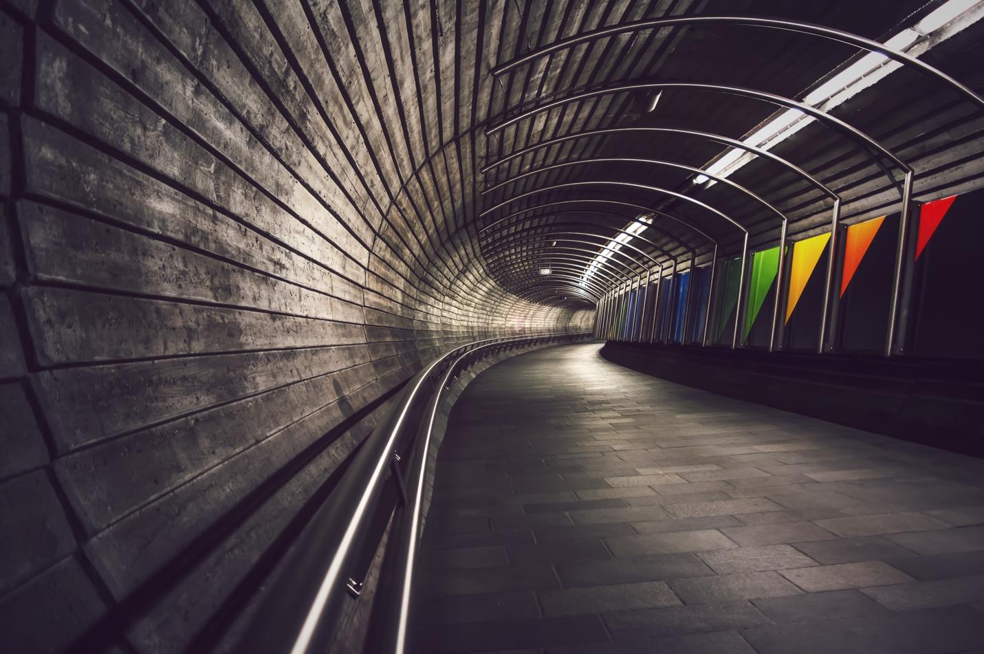 A tunnel with a walkway and colorful lights

Description automatically generated