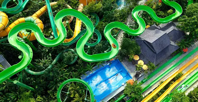 A vibrant water park in Bali featuring thrilling water slides, lush tropical surroundings, and families enjoying a fun-filled day under the sun.