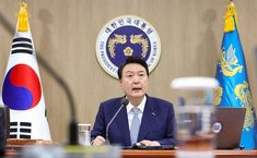 This contain President Yoon Suk Yeo sitting at a table in front of two flags