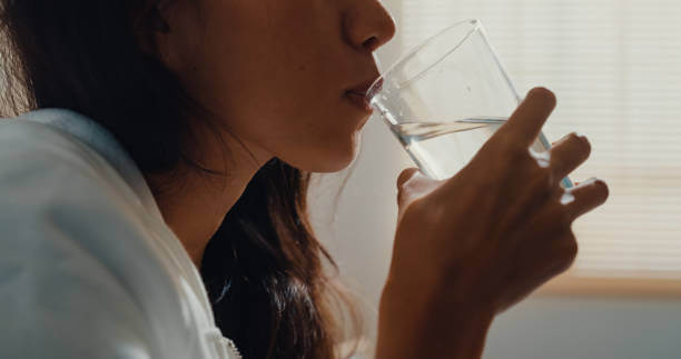 A woman drinking a glass of water, highlighting the importance of hydration for liver detox and overall well-being.