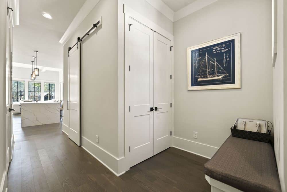 Mudroom with a bench and storage closet concealed behind the white double door.