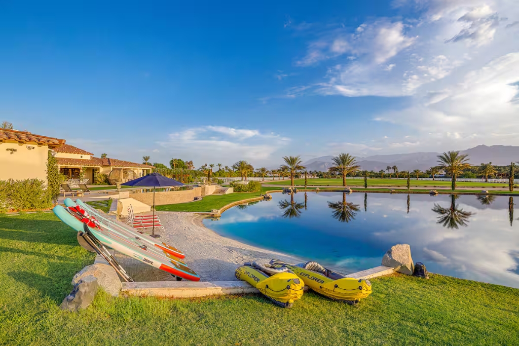 green grass and a man made lake with canoes in a desert airbnb in thermal california 