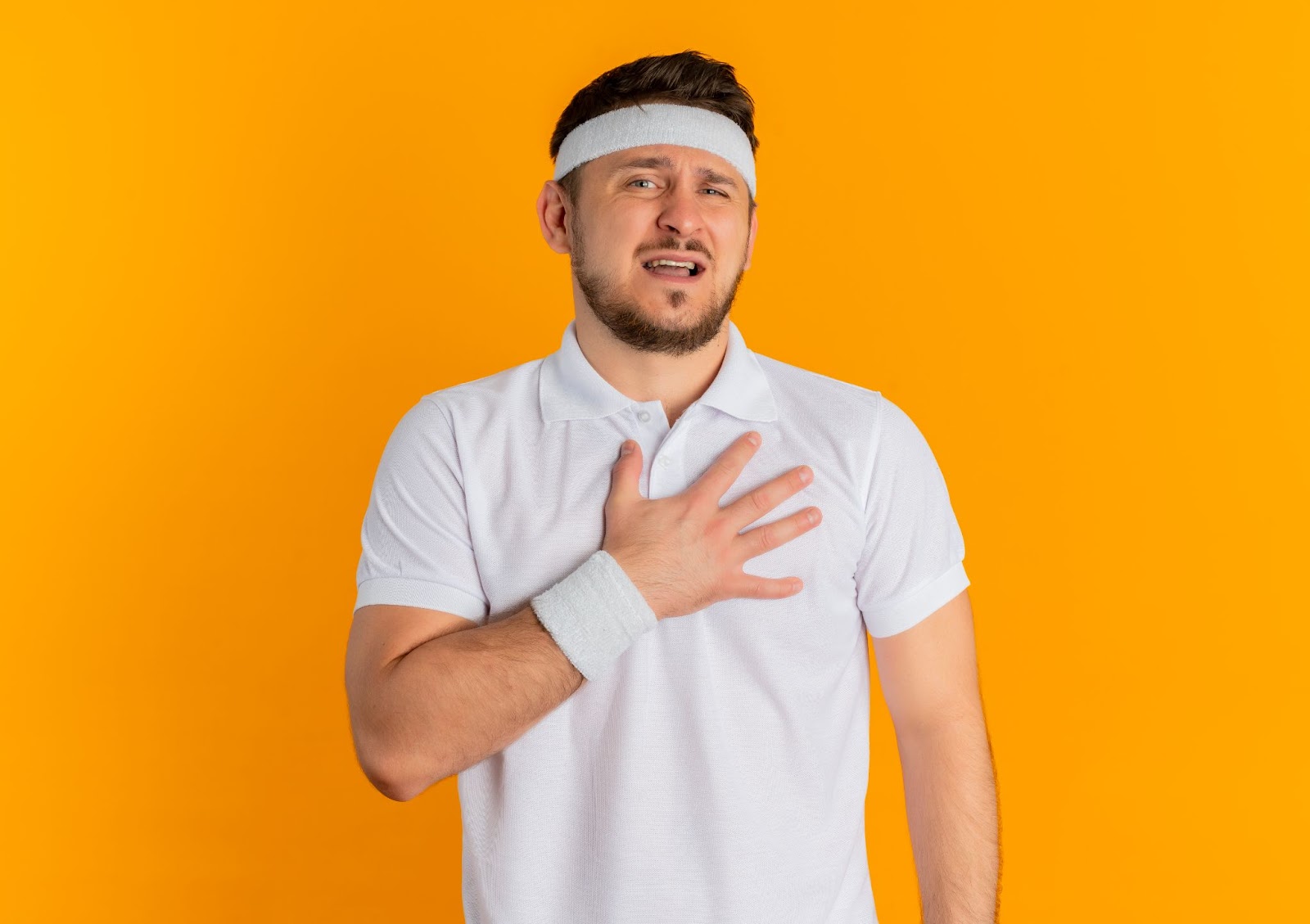 A man in workout clothes touches his painful pectoral muscles.