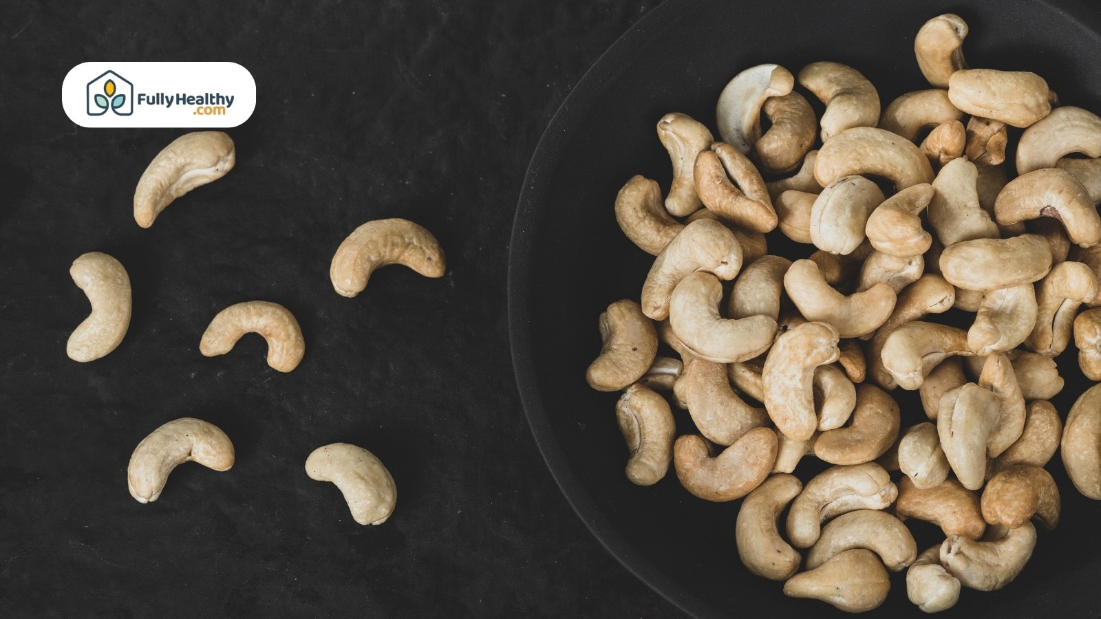 Bowl of cashew nuts with scattered pieces on dark background