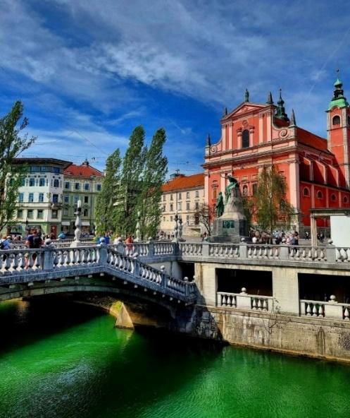 A bridge over a river with a bridge and a building in the background

Description automatically generated