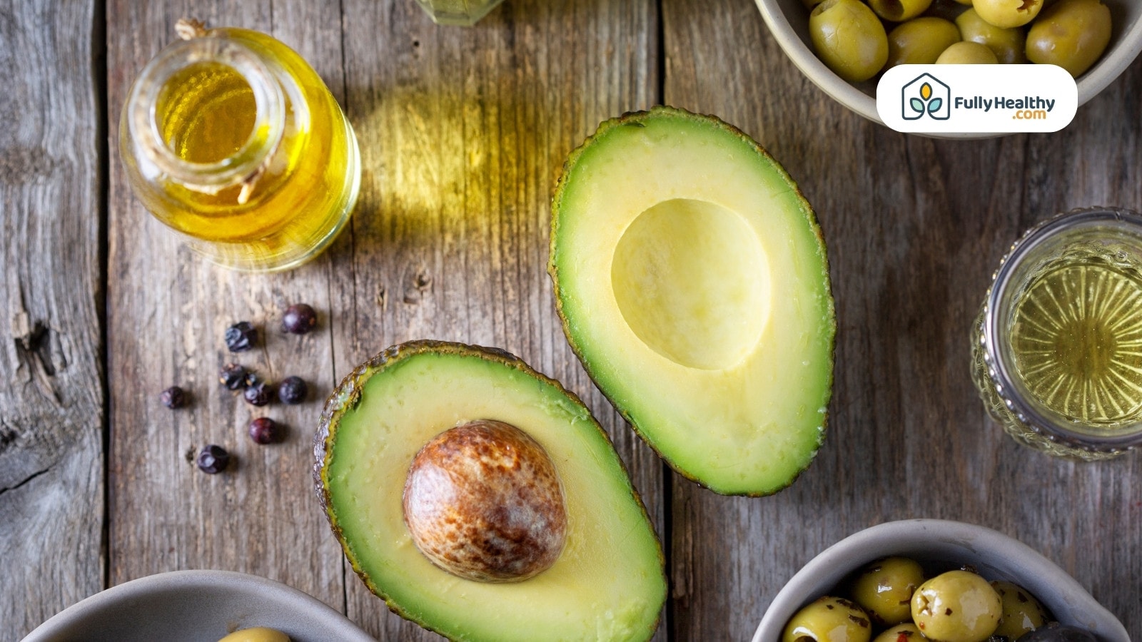 Top view of avocados and olive oil on wooden surface