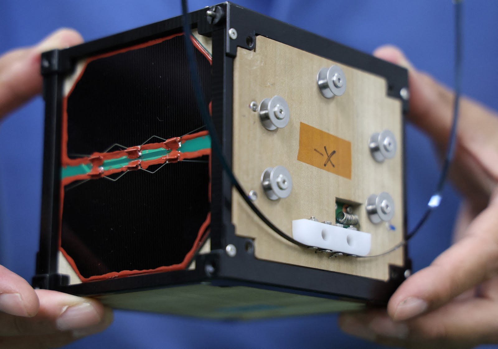 Takao Doi holds an engineering model of LignoSat during an interview with Reuters at his laboratory at Kyoto University in Kyoto