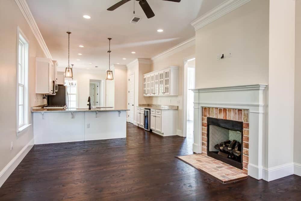 Living area with a ceiling fan and a glass-enclosed fireplace framed with a brick mantel.
