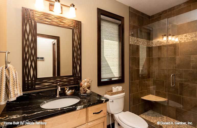 Another bathroom with a walk-in shower, a toilet, and a marble top vanity adorned with a decorative mirror.