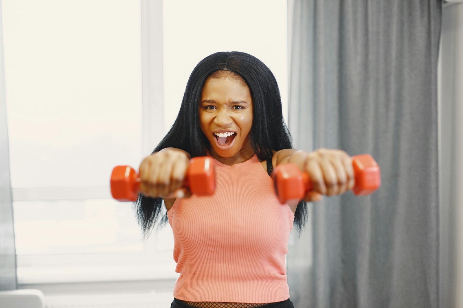 A woman lifts hand weights in her home.