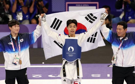 This contain an image of  South Korea martial holding up their flags in front of them as they stand on the ice