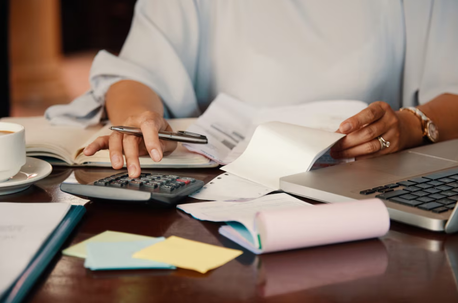 Una persona revisando documentos financieros y utilizando una calculadora