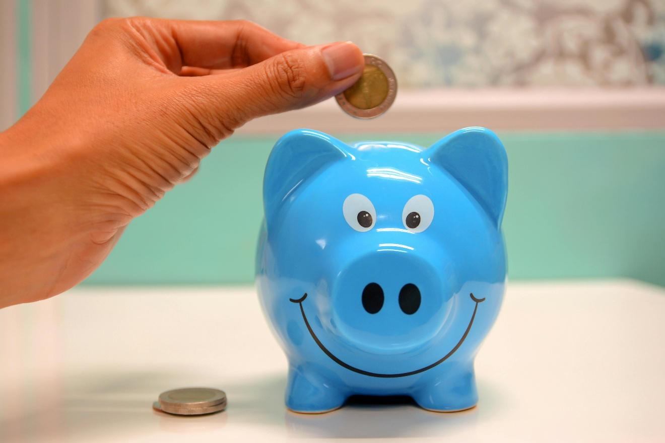 A hand putting a coin into a blue piggy bank

AI-generated content may be incorrect.