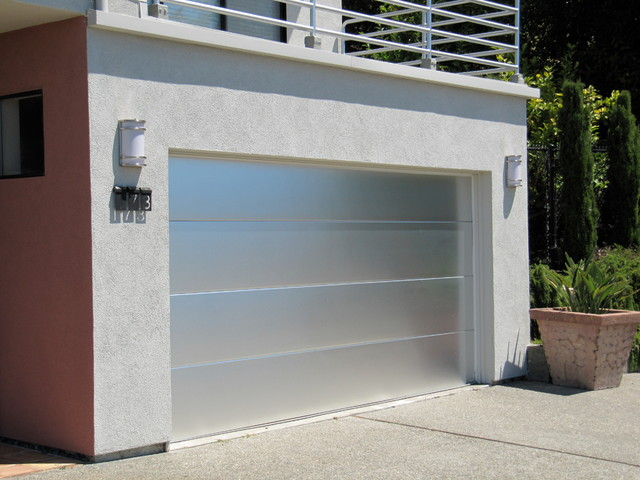 a modern aluminum garage door with a sleek, minimalist design. The door features horizontal paneling and a smooth metallic finish that complements the building's contemporary architectural style