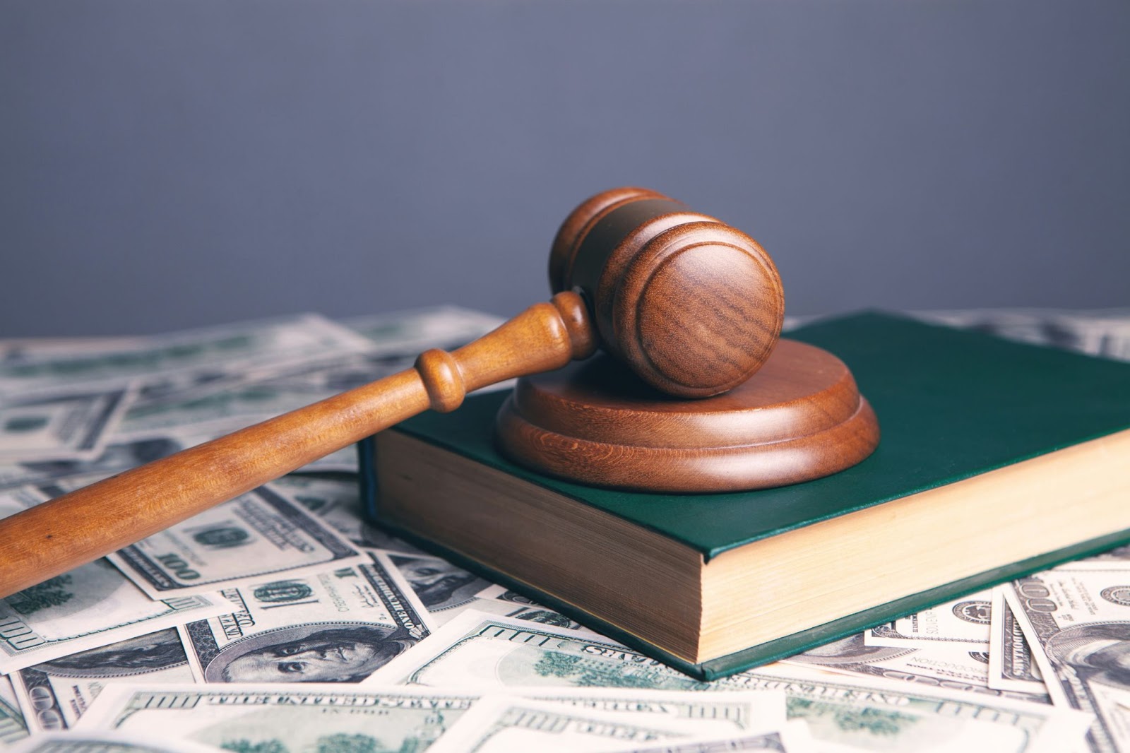 A gavel and a book with hundred dollar bills, symbolizing the new buyer commission laws 