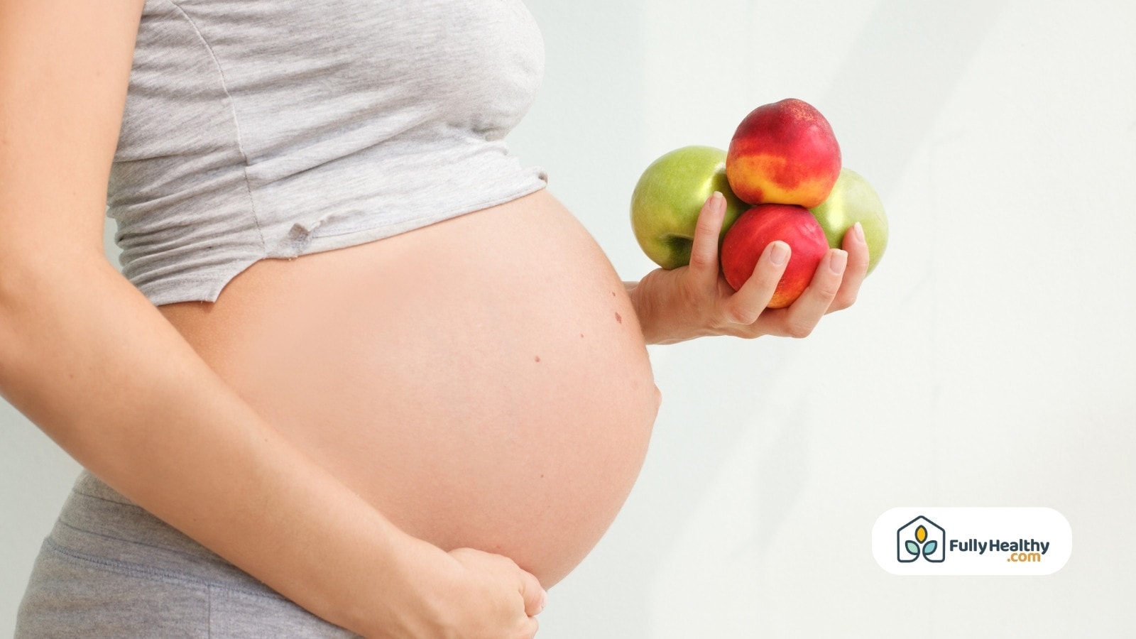 Pregnant woman holding fresh apples and peaches