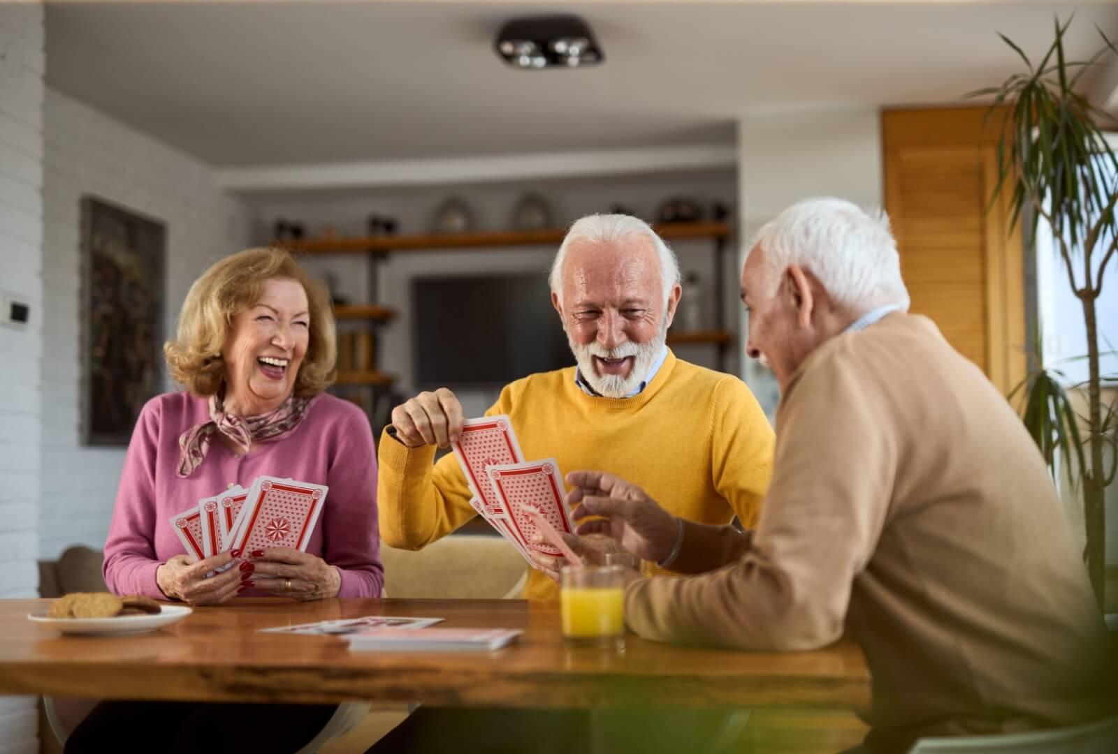 A group of seniors in memory care enjoying a card game together with enlarged cards. The larger cards are easier to see.