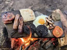 a stone from a rock shaped into a flat rock girddle for cooking in the forest as one of the A tin can designed  into a stove used as emergency cooking Hacks When camping