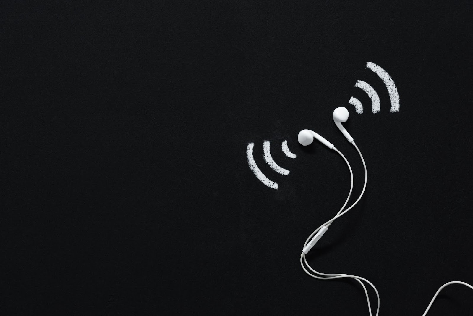 (White earphones with chalk-drawn wireless signal symbols on a black background, inviting you to "Name That Sound.)