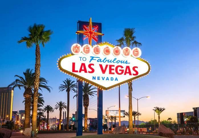 A sign with palm trees and Welcome to Fabulous Las Vegas sign in the background
Description automatically generated