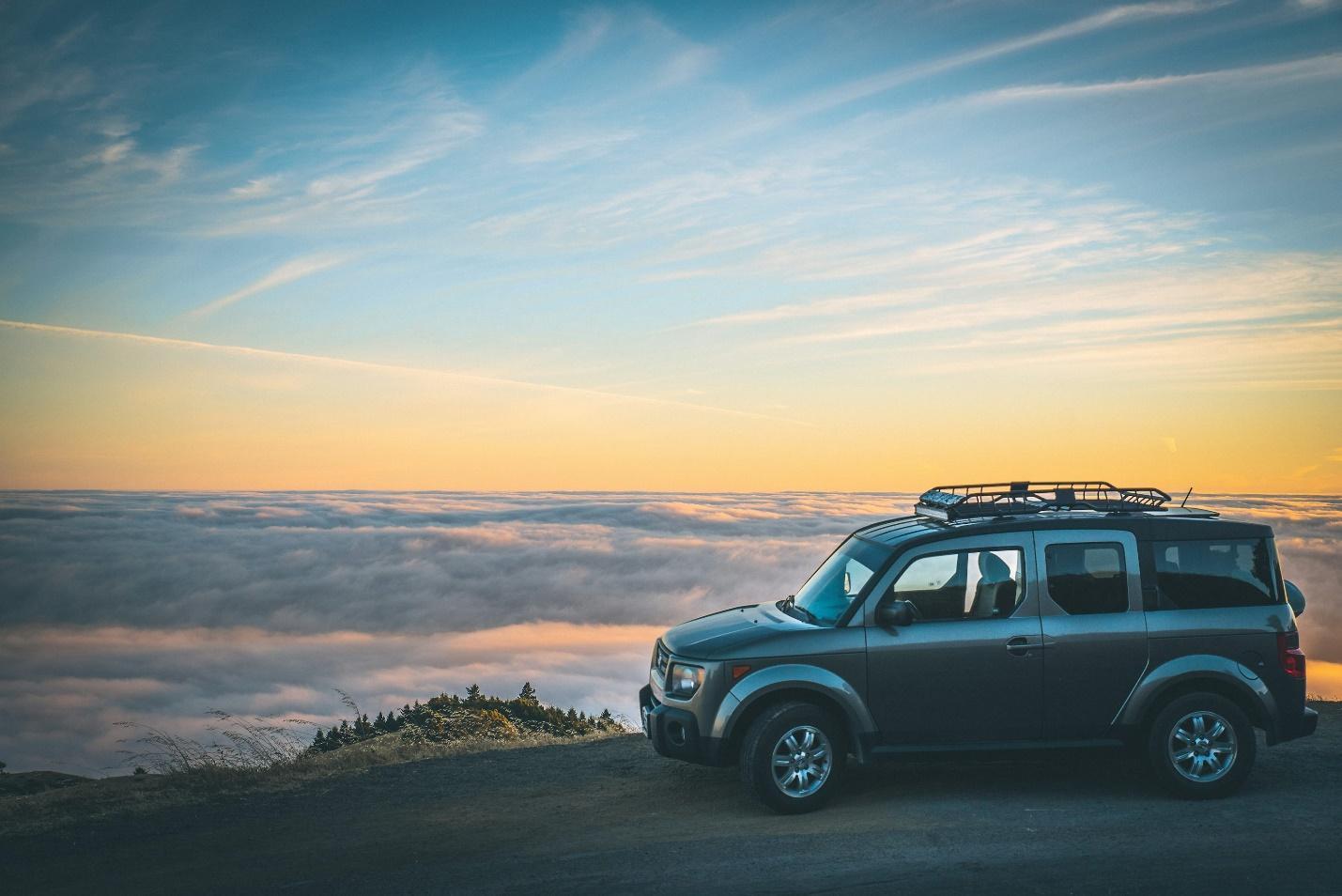 grey SUV beside sea of cloud