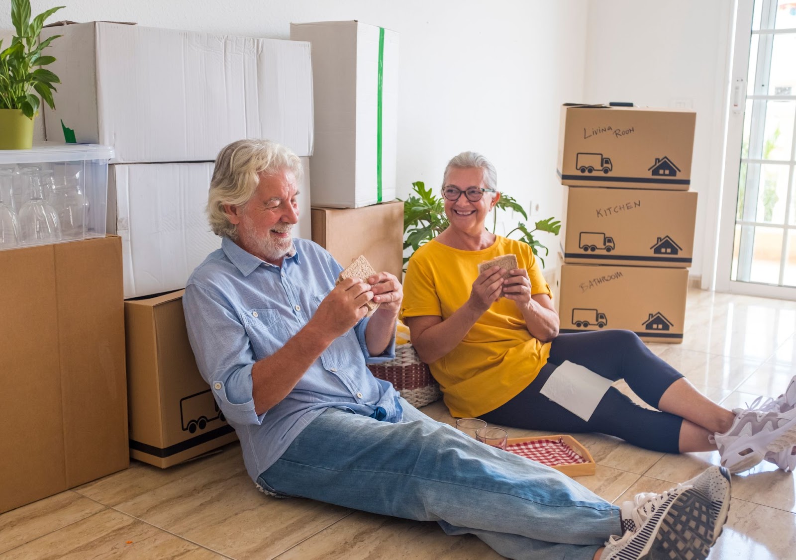 A happy senior couple take a break from packing to enjoy lunch together.