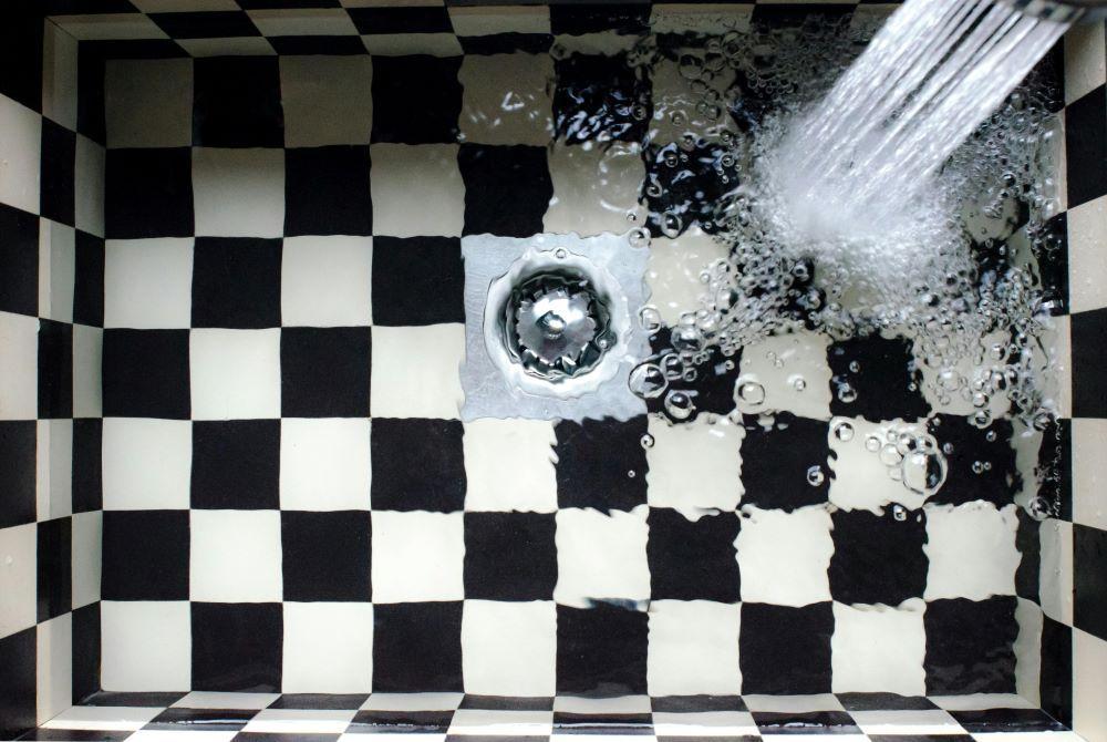 A drain in a kitchen with water