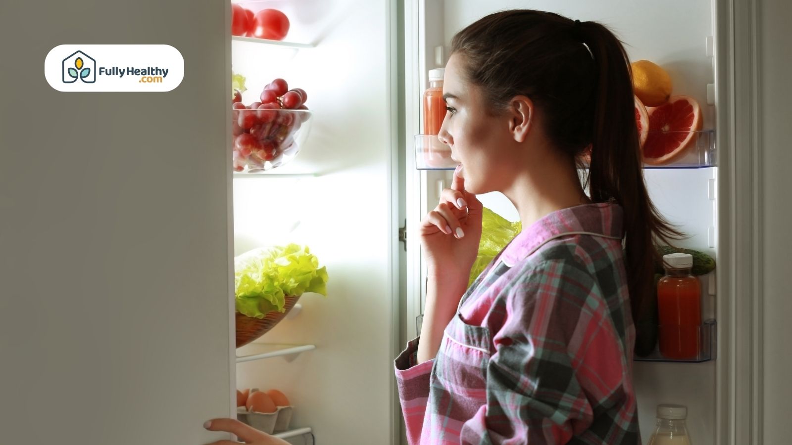 Woman looking inside refrigerator full of fruits vegetables and juice bottles