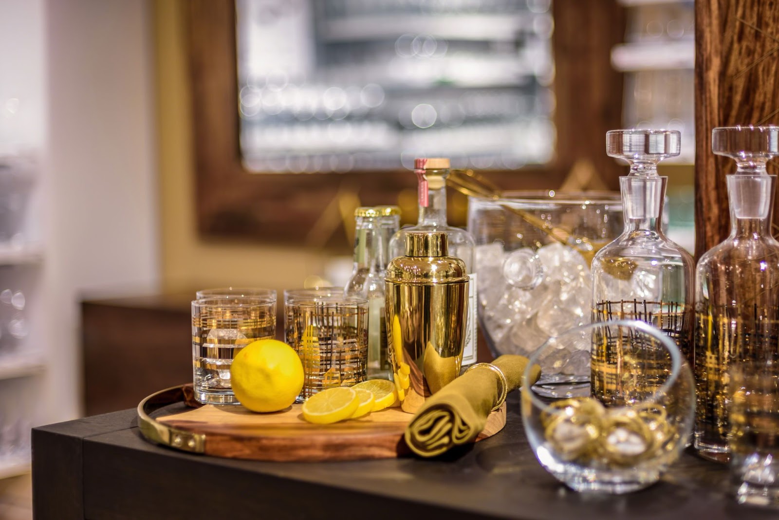 Glassware, lemons, utensils, and ice on a bar. 