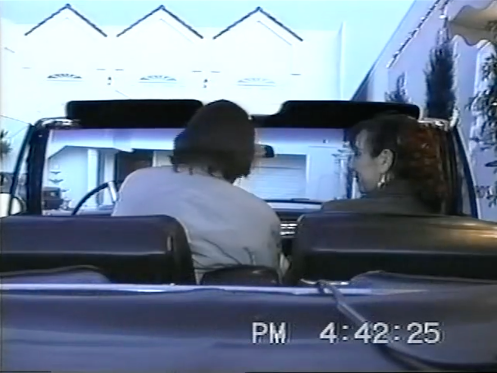 Still of a tape of a man driving a convertible with a woman looking at him.